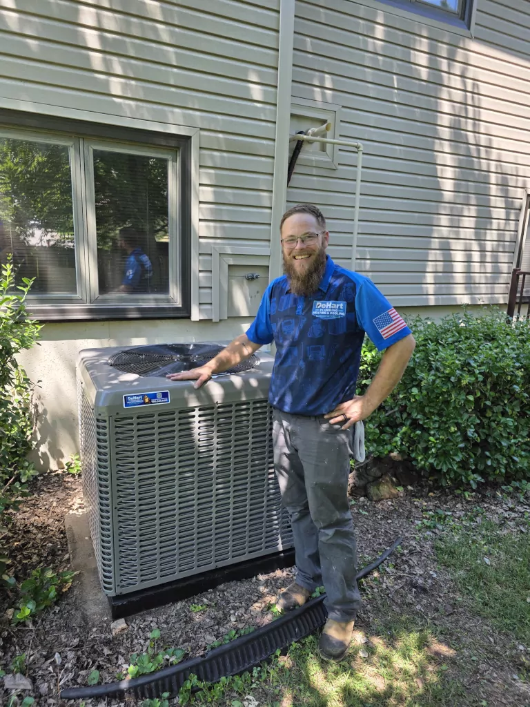 De hart tech smiling besides heat pump